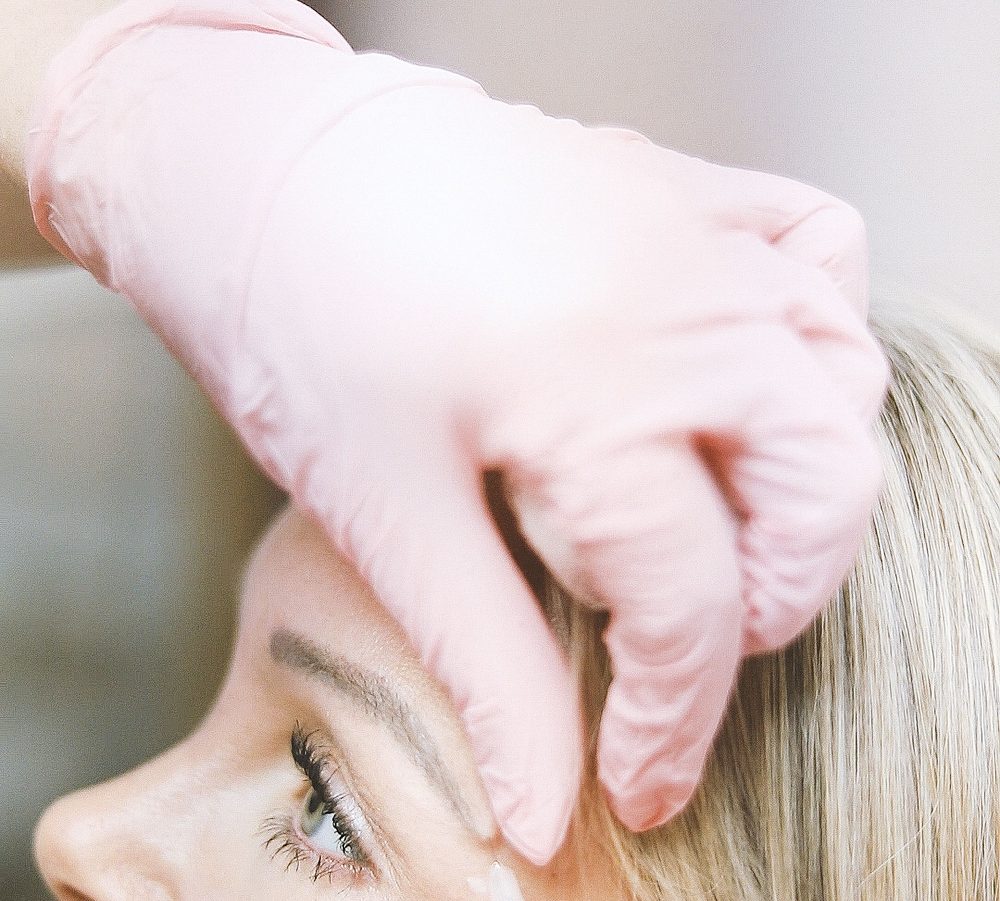 Gloved hands administering a neurotoxin injection above the brow